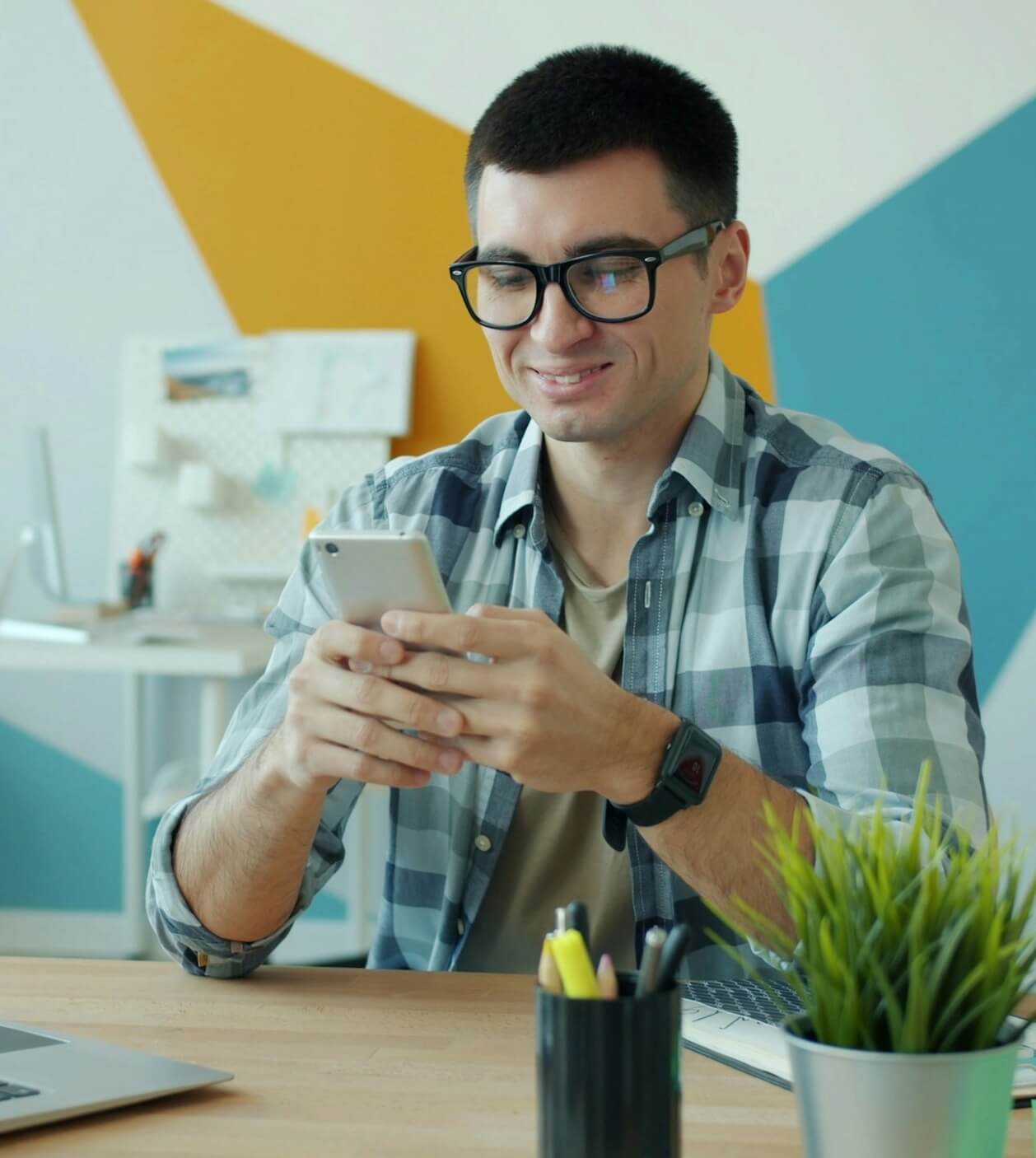 Buyer browsing freelancers on a phone beside a laptop