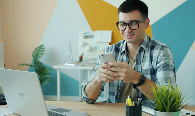 Buyer browsing freelancers on a phone beside a laptop